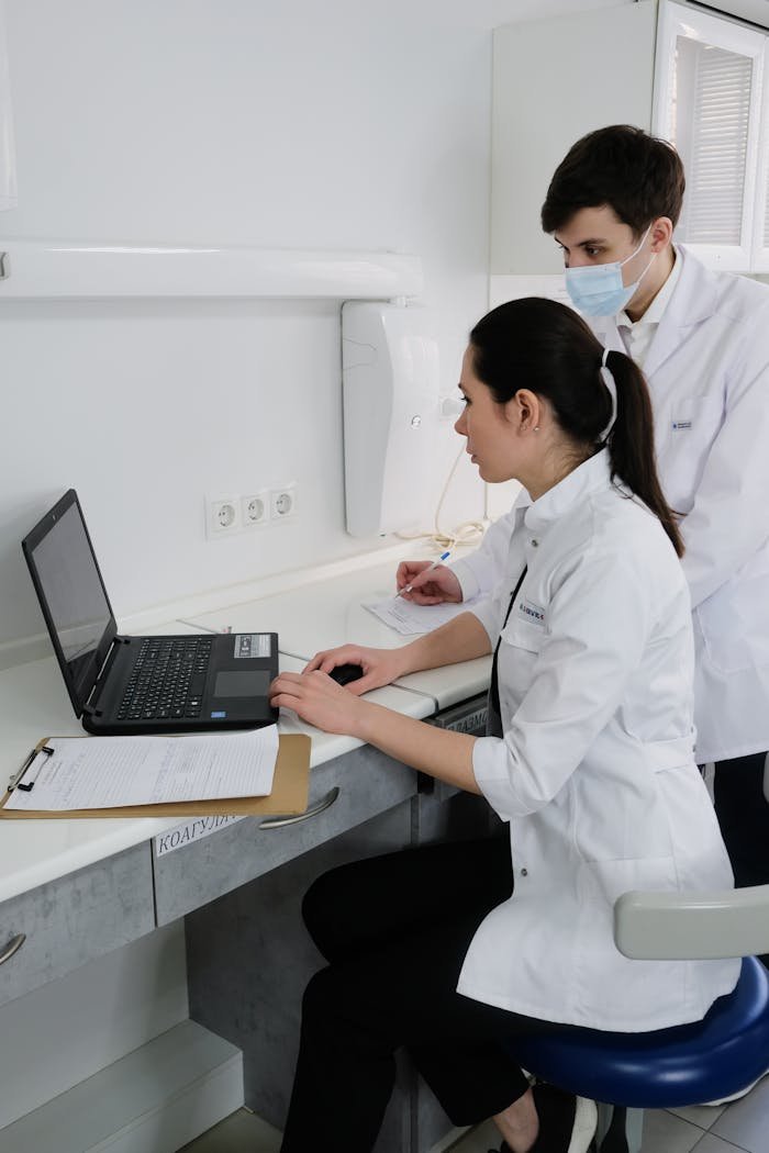 Doctors collaborating on a project using a laptop in a clinical setting.